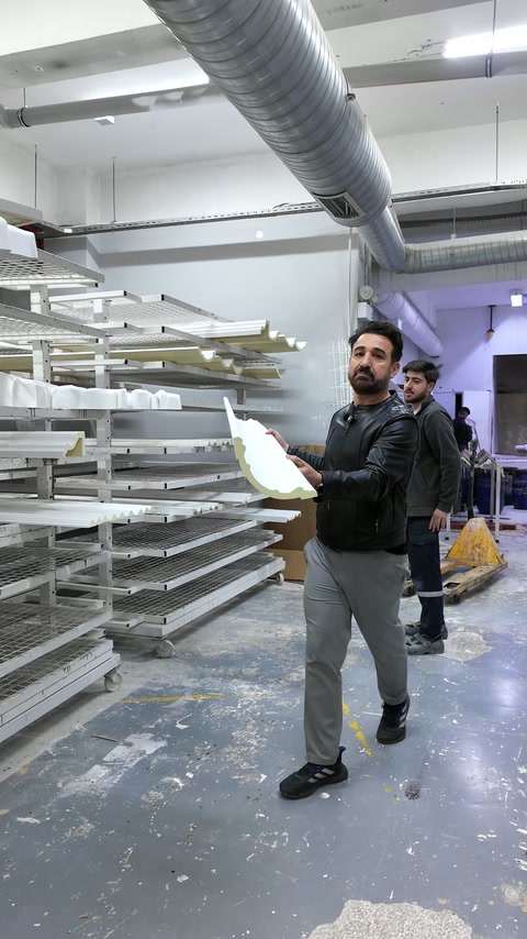 Elemento decorativo branco curvo mostrado junto a estantes de produção organizadas