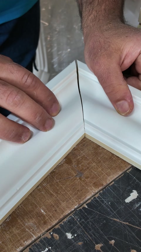 Handwerker prüft eine Gehrungsverbindung zwischen geformten Polyurethan-Profilen