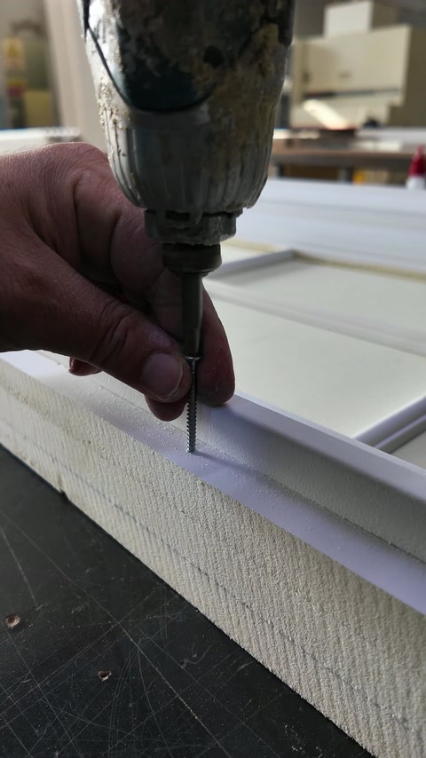 Handwerker bohrt durch die Kante eines Polyurethan-Paneels
