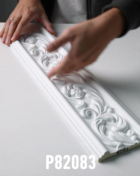 Mano tocando friso de pared ornamentado de poliuretano blanco con relieve floral