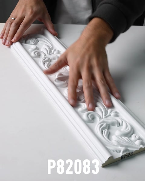 Manos deslizándose por la textura de la superficie de una moldura de pared ornamentada de poliuretano