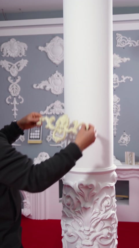 Prožni ornament slonokoščene barve, nameščen na okroglo površino stebra