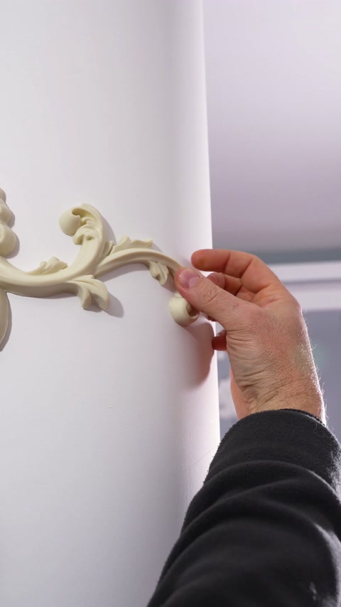 Prsti pritiskajo konico ornamenta ob ukrivljeno deblo stebra