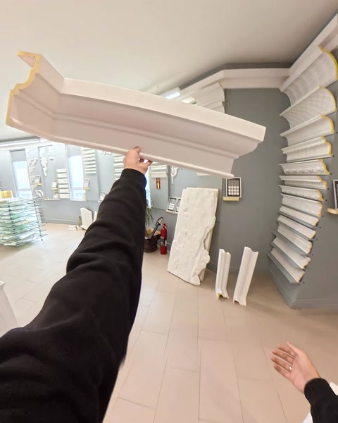 Kéz tart egy hosszú koronapárkány darabot a bemutatóteremben