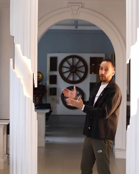 Presenter gesturing beside illuminated columns in decorated showroom
