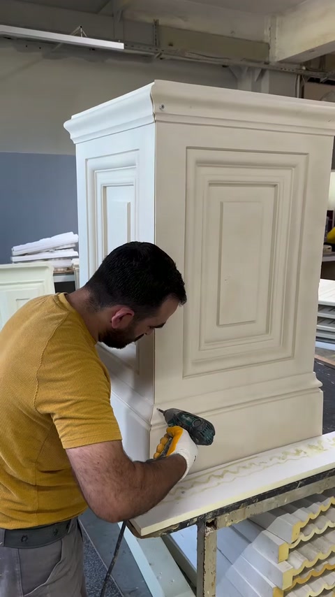 Un ouvrier prépare le bord inférieur d’un piédestal à panneaux.
