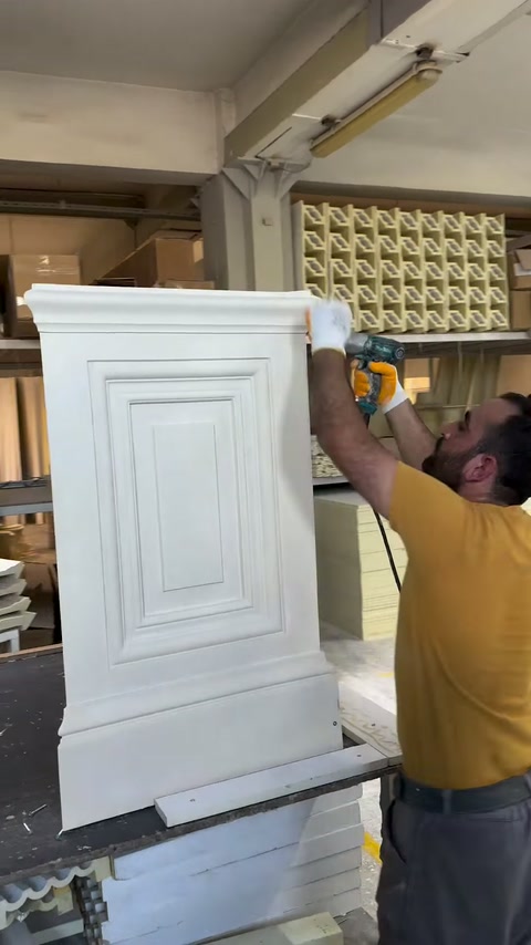 Deux techniciens alignent la partie supérieure pendant l’assemblage d’un piédestal décoratif.