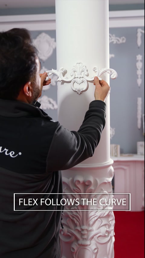 Un installateur positionne un motif décoratif flexible autour d’une colonne courbe.