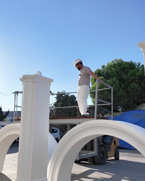 Worker on scaffolding aligning the arch over a column body