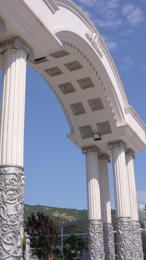 Detail z nízkého úhlu zvýrazňuje kanelované sloupy a kazetový oblý oblouk.