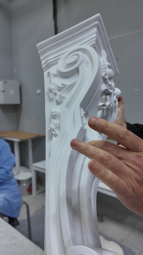 Detailní pohled zvýrazňuje vrstvenou volutu a listový reliéf konzoly