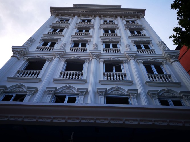 Klassische Hotel-Fassade mit Polyurethan-Ornamenten und eleganten Details <h2>Klassische Gestaltung mit Polyurethan-Elementen</h2><p>Die Fassade nutzt <strong>Polyurethan</strong>, um detailreiche Ornamente, Reliefs und Säulen effizient umzusetzen. Die hohen, vertikal ausgerichteten Pilaster verleihen dem Gebäude eine deutliche <strong>Symmetrie</strong>, die durch gleichmäßig platzierte Fenster und dekorative Rahmen noch verstärkt wird.</p><p>Besondere Akzente setzen die Bogenabschlüsse über jedem Fenster, die mit feinen floralen Motiven geschmückt sind. Die klassischen Balustraden aus <strong>Polyurethan</strong> erinnern an historische Palastarchitekturen und verstärken das elegante Gesamtbild. Zwischen den Fensterachsen betonen zarte Linien und profilierte Gesimse die harmonische Struktur.</p><p>Ein kurzer Blick in die Baugeschichte zeigt, dass Balustraden und Kapitelle seit der Renaissance als repräsentative Gestaltungselemente eingesetzt wurden. In dieser Umsetzung verbinden sie Tradition mit langlebigen, modernen Werkstoffen.</p><p>Die <strong>Fassadengestaltung</strong> zeigt somit eine gelungene Kombination aus historischen Vorbildern und zeitgemäßer Umsetzung. Das Gebäude strahlt durch seine weiße Oberfläche Klarheit und <strong>Eleganz</strong> aus.</p><ul><li>Vertikale Pilaster mit feinen Kapitellen</li><li>Bogenförmige Fensterabschlüsse mit Ornamenten</li><li>Dekorative Balustraden</li><li>Feine florale Reliefs in Gesimsen</li></ul>

<p>Diese Fassade präsentiert ein Hotel mit klassischem Design und moderner Fertigung. Die Verwendung von <strong>Polyurethan</strong> ermöglicht präzise Ornamente und elegante Strukturen. Auffällig sind die vertikalen Pilaster, die eine klare <strong>Symmetrie</strong> betonen. Jedes Fenster wird von bogenförmigen Rahmen mit floralen Details akzentuiert. Reliefelemente heben die Ästhetik der Gestaltung hervor. Besonders eindrucksvoll wirken die Balustraden zwischen den Fensterzonen. Diese erinnern an historische Renaissance-Architektur. Die weiße Oberfläche unterstreicht die <strong>Eleganz</strong> der Fassade. Harmonie entsteht aus der Wiederholung symmetrischer Formen. <strong>Fassadengestaltung</strong> mit Polyurethan bietet zudem leichte und dauerhafte Lösungen. Die Dekore sorgen für Tiefe und Ausdrucksstärke. Säulen und Kapitelle zeigen die Vielfalt klassischer Stile. Florale Muster fügen sich in die Komposition ein. Diese Architektur macht ein Hotelgebäude zum Blickfang. Tradition und Moderne verschmelzen hier in einem Gesamtkonzept. Ein solcher Bau vermittelt Wertigkeit und Stil.</p>
