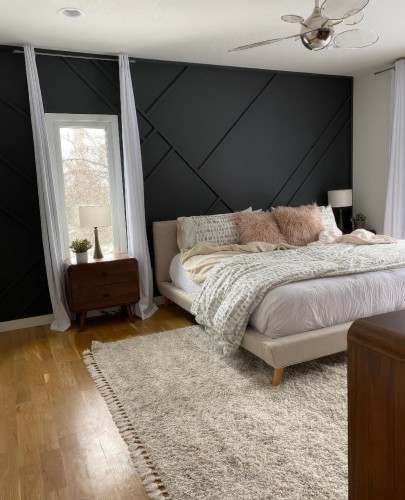 Modernes Schlafzimmer mit Polyurethan-Wanddetails und minimalistischen Möbeln <h2>Harmonie von Geometrie und Material</h2><p>Das Schlafzimmer präsentiert eine eindrucksvolle schwarze Wandgestaltung, die durch <strong>geometrische Muster</strong> in Polyurethan Tiefe und Struktur erhält. Die diagonalen Reliefs schaffen ein modernes Spiel mit Licht und Schatten, das den minimalistisch gehaltenen Raum belebt.</p><p>Die Möbel sind schlicht und funktional konzipiert. Ein neutrales, gepolstertes Bett harmoniert mit weichen Kissen und Decken, die in Beige- und Rosétönen Akzente setzen. Ergänzt wird dieser Stil durch Nachttische und eine Kommode aus Holz, deren natürliche Maserung dem Raum Wärme verleiht.</p><p>Ein flauschiger <strong>Teppich</strong> mit Fransen sorgt für eine weiche Grundlage und kontrastiert mit dem harten Linienmuster der Wand. Weiße Vorhänge rahmen das Fenster ein und verstärken den Eindruck von Luftigkeit und Klarheit. Der moderne Deckenventilator ergänzt das Design mit einem funktionalen, futuristischen Element.</p><p>Historisch gesehen knüpfen Wandreliefs an traditionelle Techniken an, wie sie in klassischer Architektur für dekorative Paneele genutzt wurden. Hier wird diese Idee in einer modernen Form neu interpretiert.</p><ul><li>Starke Kontraste durch schwarze Wand und helle Textilien</li><li>Kombination aus <strong>minimalistischen Möbeln</strong> und Holzdetails</li><li>Spannung durch geometrische Polyurethan-Strukturen</li><li>Balance von Wärme und Klarheit</li></ul>

<p>Dieses Schlafzimmer zeigt, wie klare Linien und ein raffiniertes Konzept eine ruhige Atmosphäre erzeugen. Die schwarze Akzentwand mit <strong>Polyurethan</strong>-Details verleiht Tiefe und modernistische Strenge. Holzoberflächen der Möbel bringen Wärme in den Raum. Das neutrale Bett sorgt für Komfort und Ausgleich. Weiche Kissen in Pastellfarben ergänzen den Stil. Ein heller <strong>Teppich</strong> mit Fransen intensiviert die gemütliche Wirkung. Minimalistische Nachttische steigern die Funktionalität. Ein eleganter Deckenventilator bringt Bewegung und moderne Technik. Lange Vorhänge rahmen das Fenster in klarer Vertikale. Der Einsatz von geometrischen Reliefs schafft Dynamik. Kontrast zwischen hellen Stoffen und dunkler Wand fasziniert. Naturtöne verstärken den harmonischen Gesamteindruck. Die Kombination aus Holz und Textil wirkt ausgewogen. Ein schlanker Kommodekörper betont den linearen Aufbau. Die Komposition bietet Inspiration für stilvolle Schlafzimmergestaltung.</p>