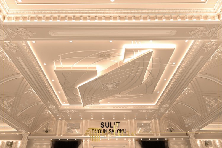 Decoração Clássica em Poliuretano para Salão de Casamentos com Iluminação Elegante <h2>Design Clássico e Contemporâneo</h2><p>O salão de casamentos é concebido com forte influência da <strong>arquitetura clássica</strong>, trazendo colunas esculpidas, molduras ornamentadas e painéis em <strong>poliuretano</strong>. Estes detalhes realçam a sensação de luxo e reforçam a estética tradicional, inspirada nos estilos históricos europeus como o Barroco e o Rococó.</p><p>No entanto, o espaço não se limita ao passado. No teto, encontramos um painel geométrico moderno em camadas, iluminado por linhas de LED embutidas. Esta integração de <strong>iluminação indireta</strong> com relevos moldados cria um equilíbrio entre tradição e inovação.</p><h2>Detalhes Ornamentais e Estilo</h2><p>As <strong>molduras decorativas</strong> e os frisos elaborados unem o salão em uma composição homogênea, enquanto os relevos florais e figuras geométricas trazem textura visual rica. A utilização de um esquema cromático em tons claros valoriza ainda mais a sensação de amplitude e elegância.</p><p>Historicamente, o uso de elementos como frisos e cartelas ornamentais remonta ao período clássico greco-romano, onde a decoração arquitetônica tinha a função de demonstrar prestígio e status social. Essa mesma sensação é aqui reinterpretada para criar um ambiente de celebração luxuosa.</p><ul><li>Detalhes em relevo floral e geométrico</li><li>Teto com iluminação em camadas</li><li>Cornijas clássicas com acabamento refinado</li><li>Atmosfera sofisticada e acolhedora</li></ul>
<p>Este salão de casamentos combina <strong>decoração clássica</strong> detalhada com recursos contemporâneos de iluminação. O espaço é definido por colunas elegantes que criam uma identidade visual refinada. As molduras em <strong>poliuretano</strong> aprimoram a sofisticação estrutural. O teto em camadas incorpora geometria moderna com um toque artístico. A iluminação indireta realça as formas e aumenta a sensação de profundidade. O uso de painéis em tons claros amplia a luminosidade do ambiente. Relevos florais adicionam delicadeza ao conjunto decorativo. Frisos ornamentais remetem à tradição arquitetônica europeia. A interação entre linhas clássicas e figuras geométricas cria contraste equilibrado. Os elementos históricos são reinterpretados dentro de um contexto festivo. O design oferece requinte sem abrir mão da funcionalidade. O conjunto cria atmosfera luxuosa ideal para cerimônias formais. A ambientação valoriza tanto detalhes minuciosos quanto volumes marcantes. Este espaço convida a experiências memoráveis em um cenário sofisticado. A composição final simboliza a união de tradição e inovação.</p>