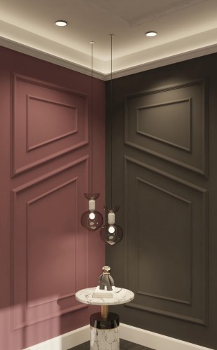 Poliuretanske zidne lajsne za moderan klasičan dnevni boravak <h2>Moderan klasičan stil sa poliuretanskim zidnim lajsnama</h2><p>Upotreba <strong>poliuretanskih lajsni</strong> na zidovima pruža mogućnost kreiranja složenih geometrijskih kompozicija koje unose dinamiku u prostor. Bordo ton sa jedne strane zida i tamno siva površina sa druge omogućavaju balans između topline i elegancije.</p><p>Dijagonalno postavljeni paneli i pravougaoni okviri oblikuju jedinstveni vizuelni ritam. Ovi detalji potiču iz tradicije klasične dekoracije, ali su ovde obrađeni na minimalistički način, što stvara pravac ka <strong>modernom klasičnom</strong> izrazu.</p><p>Plafonska rasveta sa skrivenim LED efektima naglašava linije i stvara topao ambijent. Dopunu enterijeru daju viseće svetsiljke od tamnog stakla, čiji kružni oblici donose kontrast strogoj geometriji zidova.</p><p>Stočić izrađen od belog mermera sa crnim žilama i zlatnim detaljem dodaje luksuzan akcenat. Istorijski posmatrano, slični reljefni zidni paneli potiču iz neoklasične arhitekture 18. veka, ali ovde dobijaju savremenu interpretaciju.</p><ul><li>Sklad boja između bordo i sive nijanse</li><li>Upotreba kvalitetnih materijala poput <strong>mermera</strong></li><li>Geometrijski paneli sa reljefnim efektom</li><li>Diskretna <strong>rasveta</strong> za naglašavanje detalja</li></ul>
<p>Ovaj enterijer pokazuje spoj klasičnih i savremenih vrednosti. Poliuretanske lajsne unose dubinu. Geometrijski paneli stvaraju elegantan ritam. Bordo ton dodaje toplinu prostoru. Tamno siva boja balansira atmosferu. Skrivena rasveta naglašava detalje. Viseće lampe doprinose šarmu. Mermerni stočić unosi luksuz. Kombinacija materijala stvara sklad. Površine izgledaju raskošno. Geometrija zidova uvodi dinamiku. Klasični principi preneseni su kroz jednostavnost. Moderni kontrast boja stvara harmoničan prostor. Upotreba <strong>poliuretanskih lajsni</strong> pokazuje trajnost. Enterijer dobija jasno izražen klasično-moderan karakter.</p>