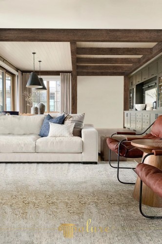 Rustieke villa-inrichting met polyurethaan houten balken en klassieke elegantie <h2>Rustieke elegantie in de woonkamer</h2><p>De woonkamer straalt een tijdloze sfeer uit dankzij de <strong>polyurethaan</strong> houten balken die het plafond een krachtig karakter geven. Deze balken voegen niet alleen rusticiteit toe, maar brengen ook visuele ritmiek en structuur in de ruimte. Het contrast tussen het donkere hout en de lichte wanden creëert diepte.</p><p>Naast de balken valt het gebruik van zachte bekleding en comfortabele meubels op. De grote lichte sofa met luchtige kussens staat in balans met de elegante zetels in roodbruine lederlook die een warm contrast toevoegen. Het vloerkleed bevat subtiele patronen en verweerde motieven die doen denken aan handgeweven structuren.</p><h2>Klassieke verfijning in detail</h2><p>De op maat gemaakte wandkasten worden geaccentueerd door metalen handgrepen en een zachte groene tint die de ambachtelijke sfeer versterken. De moderne lampen boven de zithoek benadrukken de combinatie van <strong>rustieke</strong> charme en hedendaagse stijl. Het kleurenschema met beige, grijs en gebroken wit zorgt voor harmonie.</p><p>Een kort historisch detail: plafondbalken worden al eeuwenlang toegepast in villa’s en herenhuizen, oorspronkelijk bedoeld voor structurele steun, maar later steeds vaker als esthetisch element. Hier zien we hoe dit traditionele bouwkenmerk in een moderne interpretatie opnieuw tot leven komt.</p><h2>Decoratieve accenten</h2><ul><li>Contrasterende texturen zoals hout en linnen</li><li>Geometrische vormen in tafels en stoelen</li><li>Natuurlijke lichtinval die de ruimte vergroot</li><li>Rustige kleuren die harmonie en klasse uitstralen</li></ul><p>Het resultaat is een leefruimte waarin <strong>klassieke</strong> stijl, <strong>villa</strong>-comfort en <strong>hout</strong>structuur samenkomen in een sfeervolle compositie.</p>
<p>Het interieur toont een klassieke villa met een duidelijke rustieke sfeer. De zichtbare <strong>houten</strong> balken benadrukken de natuurlijke uitstraling. De lichte bekleding van de sofa vormt een harmonieus contrast. Warme lederachtige stoelen voegen comfort en diepte toe. Het vloerkleed met verweerde motieven versterkt de authentieke sfeer. De grote ramen laten overvloedig licht binnen. Polyurethaan balken geven de kamer een duurzame charme. Subtiele details in kussens en stoffen zorgen voor variatie. De op maat gemaakte kasten voegen praktische elegantie toe. Het geheel verenigt moderne en klassieke elementen. Het houtpatroon blijft dominant in de compositie. De verlichting accentueert texturen effectief. De ruimte ademt balans en sereniteit. De geometrische lijnen van meubels brengen eigentijdse precisie. De combinatie van <strong>rustieke</strong> structuur en <strong>klassieke</strong> allure maakt de inrichting uniek.</p>