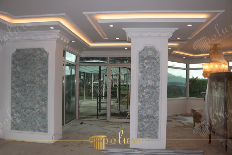 Elegant polyurethane details in classical living room design with harmony <h2>Polyurethane Elegance in Classical Living Room Design</h2><p>The refined application of <strong>polyurethane</strong> details in classical living room design introduces a combination of durability and aesthetic beauty. The columns, framed with ornate molding, emphasize grandeur while the textured decorative panels enclosed within them create incredible visual depth. The panels display a mosaic-like surface texture in soft gray-blue shades, resembling hand-applied finishes that add both charm and serenity.</p><p>The ceiling showcases layered recesses, highlighted by indirect lighting and detailed trimming. These recessed lines create a sense of height and expansiveness, while the integrated spotlights bring focus to the architectural accents. The use of <strong>ornamental molding</strong> around the edges mirrors classical design traditions inspired by Greco-Roman interiors, where refined details reinforced balance and proportion.</p><p>The design demonstrates a thoughtful use of <strong>geometric alignment</strong> and textured ornamentation, with the irregular yet harmonious motifs on the wall panels bringing contrast to the clean white framing. This dialogue between order and artistry keeps the classical style lively and engaging.</p><h2>Decorative Patterns and Historical Touch</h2><p>Historically, intricate decorative elements were used in grand halls to represent prestige. In this living room, the spirit of such tradition continues, using modern <strong>polyurethane panels</strong> that replicate the sophistication and delicacy of historical motifs. The interplay of angular lines on the ceiling with the soft textured effect of the wall panels ensures the design remains both timeless and adaptable.</p><p>This approach demonstrates how <strong>classical decoration</strong> can still inspire contemporary interiors. By blending light, proportion, and decorative detailing, the design conveys an atmosphere that is both stately and welcoming.</p>
<p>The classical living room design highlights the elegance of <strong>polyurethane</strong> decoration. The detailed wall panels showcase textured blue-gray motifs framed in crisp white borders. Ceiling design combines layered recesses with integrated square and linear forms. Indirect lighting enhances the refined <strong>ornamental molding</strong>. Decorative motifs echo historical classical architecture. The balanced use of color and texture amplifies harmony. Textured surfaces add depth to plain structural lines. The interplay between geometry and softened textures creates character. <strong>Geometric alignment</strong> ensures visual balance. Classical influence is seen in the refined column framing. Subtle details build an atmosphere of grandeur. Decorative <strong>polyurethane panels</strong> bring durability as well as style. The reflective balance of ornaments shows timeless design principles. The rich texturing avoids monotony through variation. Classical living room arrangement achieves elegance through layered light. Ultimately, the blend of detail and proportion provides a welcoming classical aesthetic.</p>