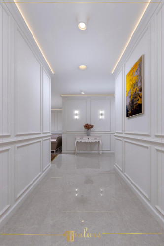 Nowoczesno-klasyczny korytarz z listwami poliuretanowymi <h2>Elegancja listw poliuretanowych w korytarzu</h2><p>Korytarz został zaprojektowany w duchu stylu nowoczesno-klasycznego, gdzie <strong>listwy poliuretanowe</strong> wprowadzają dekoracyjny i precyzyjny podział przestrzeni. Te geometryczne ramy nadają wnętrzu spójny rytm i uporządkowaną harmonię, a jednocześnie nawiązują do estetyki rezydencji z minionych epok.</p><p>Podłoga wykończona została płytami imitującymi <strong>marmur</strong>, które w połączeniu z subtelnym połyskiem wzmacniają wrażenie luksusu. Dzięki refleksom światła cała przestrzeń wydaje się większa i bardziej reprezentacyjna.</p><p>Konsola o giętych nogach stanowi delikatne nawiązanie do klasycznej sztuki użytkowej, a umieszczony nad nią obraz w barwach żółci i czerni wnosi mocny akcent nowoczesności. Zastosowanie punktowych <strong>kinkietów</strong> oraz dyskretnych opraw LED w suficie sprawia, że każdy detal dekoracyjny zostaje odpowiednio wyeksponowany.</p><p>Styl nowoczesno-klasyczny, inspirowany dawnymi pałacami, często wykorzystywał elementy panelowych podziałów i sztukaterii. W tym projekcie ta tradycja została zreinterpretowana poprzez użycie lekkich i trwałych elementów z <strong>poliuretanu</strong>, co pozwala na łatwą aranżację i utrzymanie czystości.</p><ul><li><strong>Geometria</strong> paneli ściennych nadaje rytm i eleganckie proporcje.</li><li><strong>Oświetlenie LED</strong> podkreśla światłocień i tworzy atmosferę lekkości.</li><li>Akcent kolorystyczny obrazu przełamuje harmonię bieli.</li></ul>

<p>Korytarz w stylu nowoczesno-klasycznym łączy biel i elegancję w spójną aranżację. Listwy z <strong>poliuretanu</strong> nadają ścianom geometryczne podziały. Subtelne detale tworzą ponadczasowy charakter. Połyskująca podłoga przypominająca <strong>marmur</strong> odbija światło. To rozwiązanie powiększa optycznie przestrzeń. Konsola w klasycznym stylu wnosi lekkość i balansuje aranżację. Obraz w intensywnej żółci jest mocnym kontrastem. Dedykowane <strong>kinkiety</strong> podkreślają linearność układu. Oświetlenie LED równomiernie rozjaśnia detal. Dzięki temu wnętrze jest eleganckie i nowoczesne jednocześnie. Styl ten odwołuje się do dawnych tradycji sztukaterii. Zastosowane proporcje tworzą rytm i harmonię. Powierzchnie są łatwe w utrzymaniu i trwałe. Wnętrze łączy funkcjonalność z estetyką. Całość stanowi przykład połączenia minimalizmu i klasyki.</p>