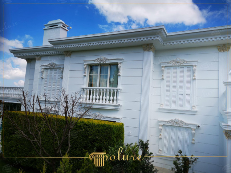 Eleganckie klasyczne zdobienia elewacji z poliuretanu dla willi <h2>Elegancja klasycznej elewacji</h2><p>Elewacja willi została zaprojektowana w stylu klasycznym z wyraźnym akcentem na <strong>symetrię</strong> i wyważone proporcje. Dekoracje z <strong>poliuretanu</strong> obejmują bogate gzymsy, zdobienia wokół okien oraz efektowne balustrady, które podkreślają reprezentacyjny charakter budynku.</p><p>Na szczególną uwagę zasługują motywy roślinne oraz geometryczne <strong>ornamenty</strong> umieszczone nad oknami, które dodają fasadzie lekkości. Balustrady o klasycznych proporcjach nawiązują do tradycji antycznych loggii, nadając całości wrażenie harmonii.</p><p>W starożytnej architekturze europejskiej elementy takie jak gzymsy, pilastry czy zdobione fryzy symbolizowały prestiż i trwałość. Dzisiejsze rozwiązania oparte na lekkim poliuretanie pozwalają osiągnąć podobny efekt wizualny, bez obciążania konstrukcji.</p><ul><li>Detal gzymsu podkreśla linię dachu</li><li>Zdobienia wokół okien nadają rytm kompozycji</li><li>Złote akcenty wzbogacają białą elewację</li><li><strong>Klasycyzm</strong> łączy się z funkcjonalnością nowoczesnych materiałów</li></ul><p>Całość prezentuje się jako ponadczasowa kompozycja, w której <strong>estetyka</strong> i trwałość idą w parze z elegancją i nowoczesnością.</p>

<p>Ta klasyczna willa zachwyca harmonijną elewacją. Zastosowane elementy z <strong>poliuretanu</strong> zapewniają finezję. Balustrady podkreślają reprezentacyjny charakter fasady. Zdobienia wokół okien dodają uroku i symetrii. Reliefy oraz <strong>ornamenty</strong> roślinne wprowadzają lekkość. Geometryczne linie konsol nadają całości rytm. Złocone detale kontrastują z białą powierzchnią. Gzymsy optycznie poszerzają bryłę budynku. Klasyczny styl nawiązuje do tradycji europejskiej. Nowoczesny materiał zapewnia trwałość i odporność. Poliuretanowe profile są lekkie i praktyczne. <strong>Elewacja</strong> willi emanuje elegancją i prestiżem. Każdy detal podkreśla dbałość o estetykę. Kompozycja łączy monumentalność z subtelnością. To doskonały przykład, jak tradycja i <strong>estetyka</strong> mogą współgrać z nowoczesnymi rozwiązaniami.</p>