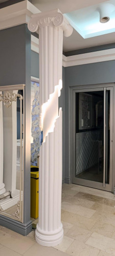 Shtyllë dekorative poliuretani me ndriçim për sallon neoklasik <h2>Shtyllë poliuretani me ndriçim dekorativ</h2><p>Kjo shtyllë elegante prej <strong>poliuretani</strong> është projektuar për të sjellë atmosferë neoklasike në çdo sallon. Forma e saj vertikale me brazda të rregullta krijon një ndjesi ritmike vizuale, ndërsa ndriçimi i integruar mban një rol estetik e funksional. Kombinimi i kapitelit me spirale të stilit jonik dhe bazës së fortë i jep shtyllës një karakter arkitektonik të fuqishëm.</p><p>Detajet e qarta gjeometrike, vijat paralele dhe qetësia e ngjyrës së bardhë reflektojnë një balancë mes <strong>klasikes</strong> dhe modernitetit. Ndriçimi i fshehur në mes të strukturës nxjerr në pah sipërfaqen, duke krijuar një efekt dramatik dhe finesë të thellë. Tekstura vertikale dhe lartësia e harmonizuar kontribuojnë në rritjen vizuale të hapësirës së brendshme.</p><p><strong>Dekorimi</strong> i tillë është i përshtatshëm për ambiente luksoze dhe sallone të stilizuara, duke e bërë shtyllën një pikë fokale të pazakontë. Në historinë e arkitekturës, format e tilla të frymëzuara nga kolonat klasike greke dhe romake kanë qenë gjithmonë simbol i prestigjit dhe stabilitetit.</p><ul><li>Kapitel me spirale tipike të stilit jonik</li><li>Ndriçim i integruar që thekson vijat vertikale</li><li>Material rezistent poliuretani</li><li>Dizajn i përshtatshëm për sallone elegante</li></ul><p>Ky kombinim i detajeve klasike me teknologjinë bashkëkohore të ndriçimit e bën shtyllën një element unik në arredimin modern.</p>

<p>Kjo shtyllë prej <strong>poliuretani</strong> me ndriçim të integruar është një zgjedhje ideale për ambiente të brendshme elegante. Përdorimi i formave gjeometrike të pastra i jep hapësirës një ritëm unik. Ndriçimi i fshehur krijon një atmosferë intime dhe të sofistikuar. Detajet vertikale theksojnë lartësinë dhe qartësinë e strukturës. Kapiteli i saj me spirale sjell një ndikim të fortë klasik. Ngjyra e bardhë ofron pastërti dhe qetësi vizuale. Ky element bashkon traditën me modernitetin në mënyrë harmonike. Brazdat e rregullta shfaqin cilësi të larta artizanale. <strong>Dekorimi</strong> me stile të tilla është i lidhur me luks dhe prestigj. Struktura prej materiali të qëndrueshëm garanton jetëgjatësi. Kombinimi i ndriçimit me formën klasike është shumë tërheqës. Ky dizajn është i përshtatshëm për ambiente luksoze dhe salla pritjeje. Historia e kolonave klasike reflektohet qartë në këtë model. <strong>Klasikja</strong> dhe neoklasikja këtu ndërthuren në mënyrë natyrale. Ky element arkitektonik mbetet një pikë qendrore e interiores moderne.</p>